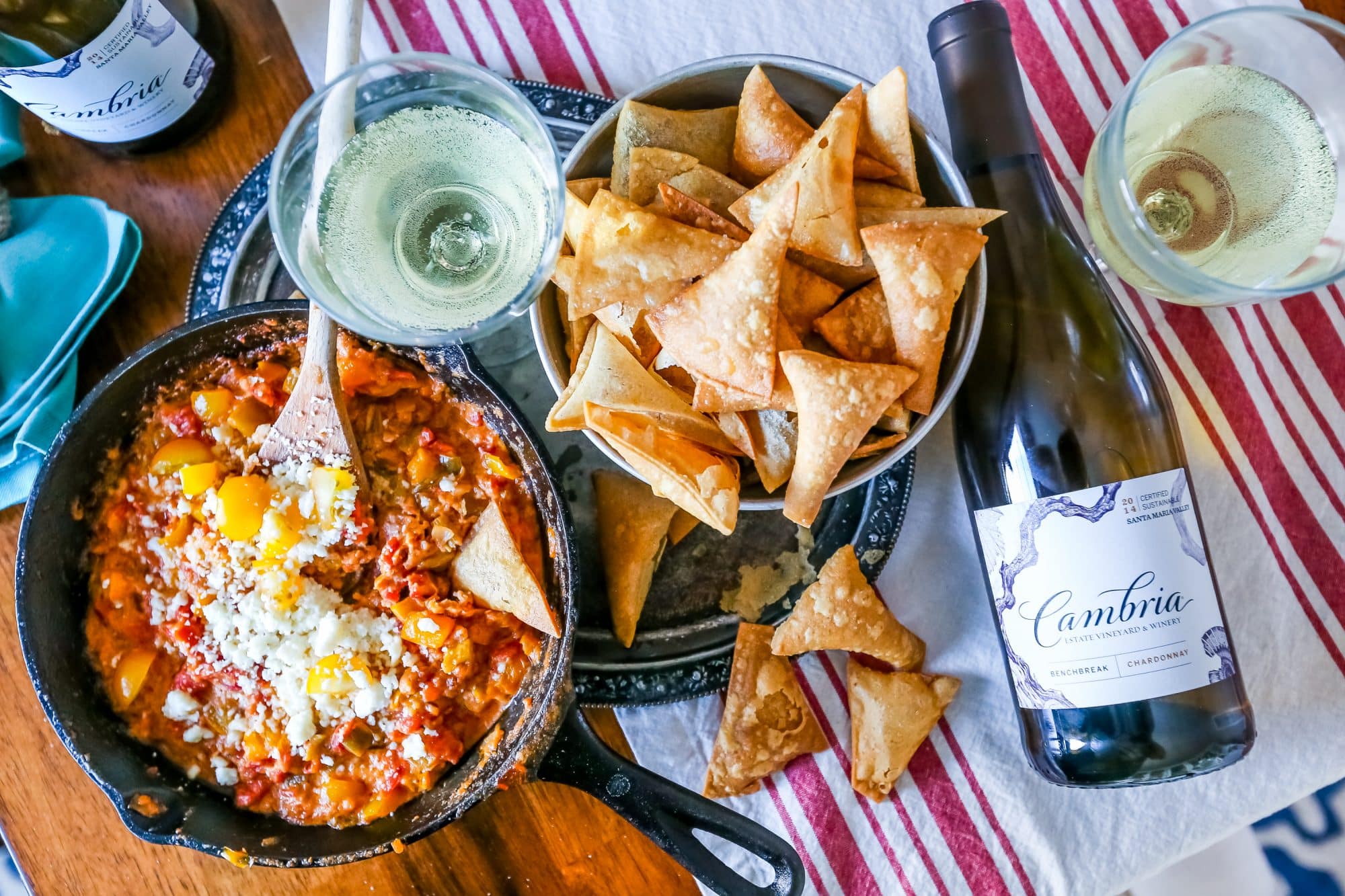 green chili, pepper, cheesy skillet with cheese on it, homemade chips in background and cambria wine.