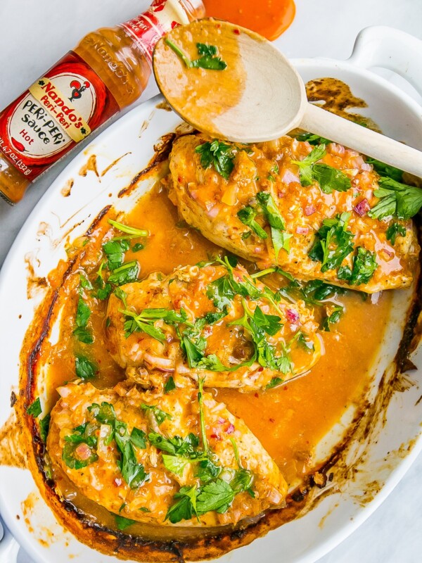 Nandos peri peri chicken served with sauce in a white dish.