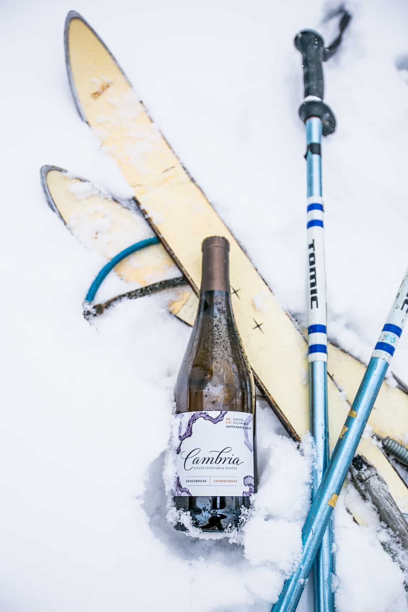 skis, ski poles, and Cambria wine in the snow
