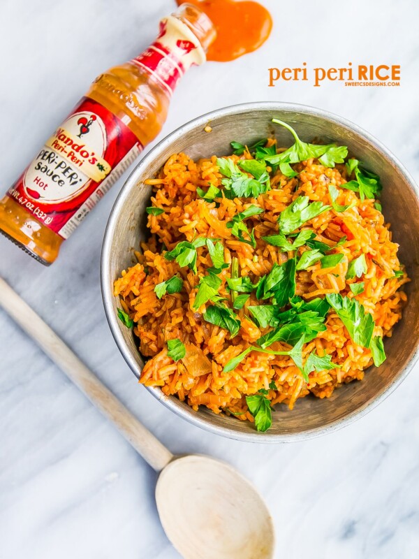 A flavorful Portuguese rice side dish with a spoon next to a bottle of spicy sauce.