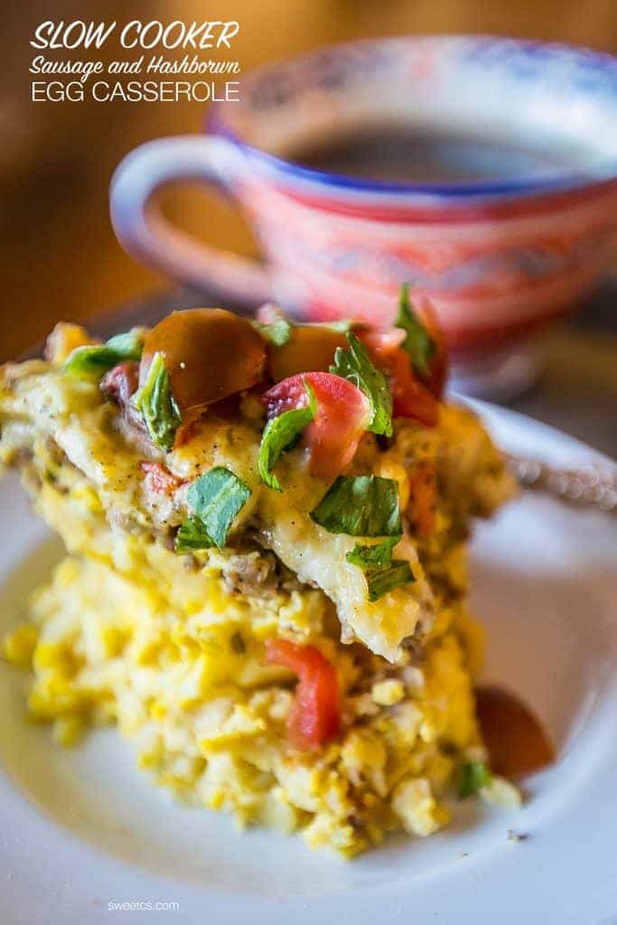 hashbrown egg casserole on a plate with tomatoes and basil on the top. tea cup in the background. 