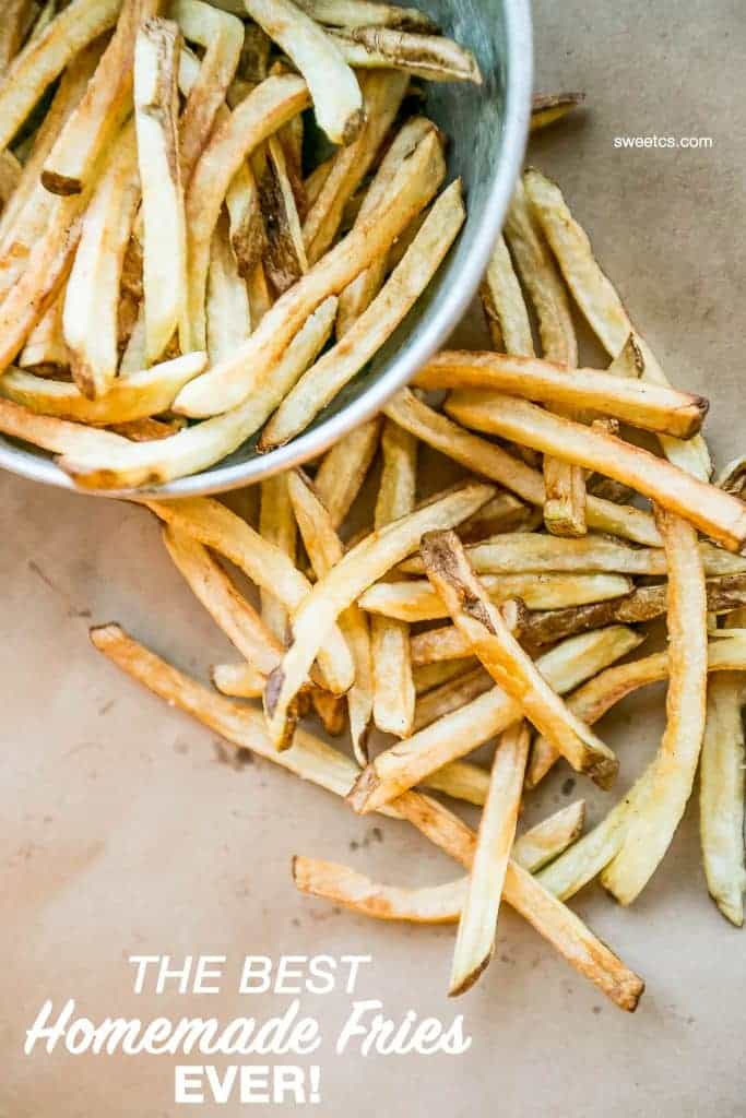 crispy baked french fries in a metal bowl spilling out onto brown paper