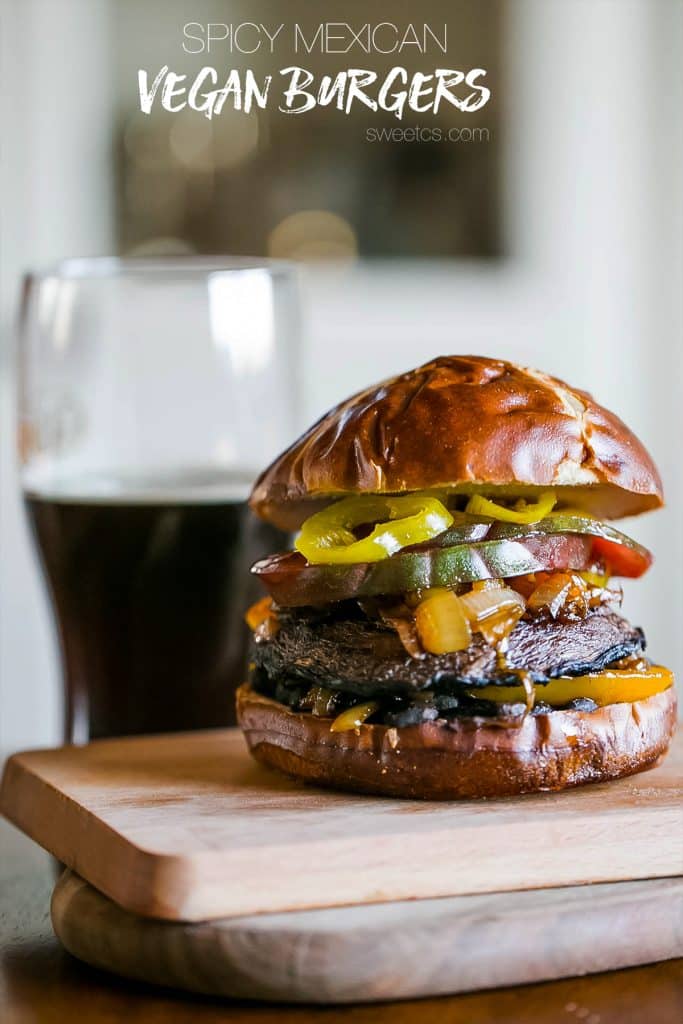 mushroom burger with tomato, banana peppers, onions, bell peppers, on a pretzel bun on a wooden cutting board