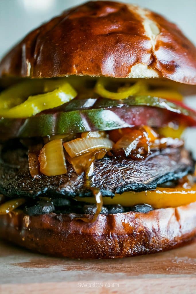 mushroom burger with tomato, banana peppers, onions, bell peppers, on a pretzel bun