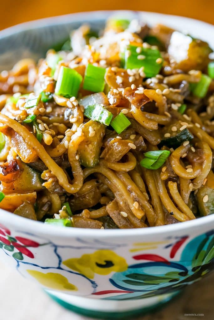 creamy vegan tahini noodles topped with sesame seeds and vegetables in a flower bowl 