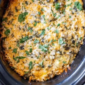 Close-up of a Slow Cooker Breakfast Casserole, baked to perfection with melted cheese and topped with chopped herbs in a slow cooker.