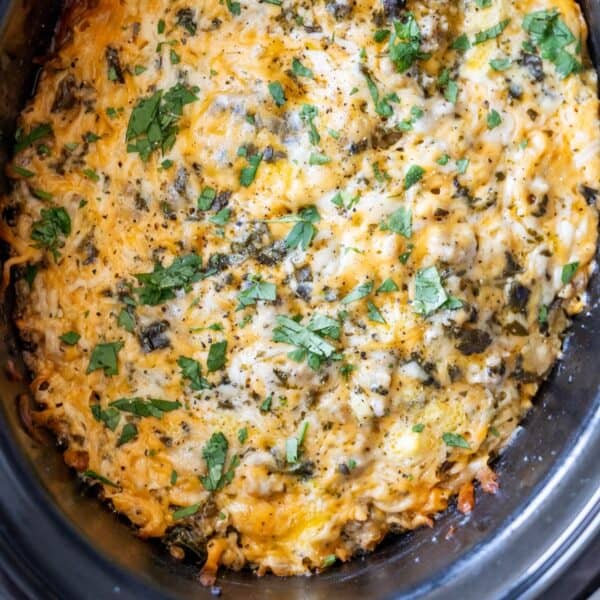 Close-up of a Slow Cooker Breakfast Casserole, baked to perfection with melted cheese and topped with chopped herbs in a slow cooker.