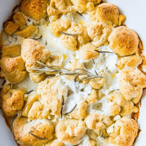 A delicious Cheesy Garlic Rosemary Bubble Bread: a baked dish of melted cheese and pull-apart bread topped with fragrant rosemary sprigs.