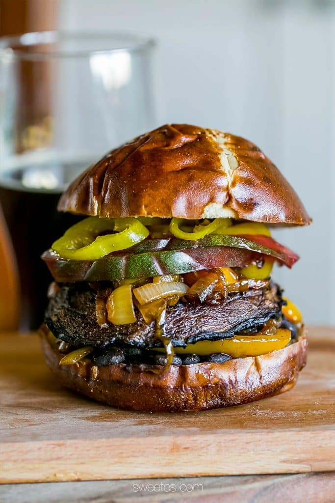 mushroom burger with tomato, banana peppers, onions, bell peppers, on a pretzel bun