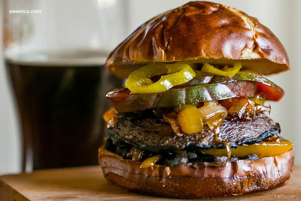 mushroom burger with tomato, banana peppers, onions, bell peppers, on a pretzel bun