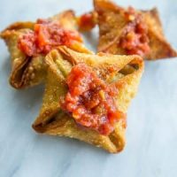Star shaped vegan samosas with tomato sauce on a marble table.