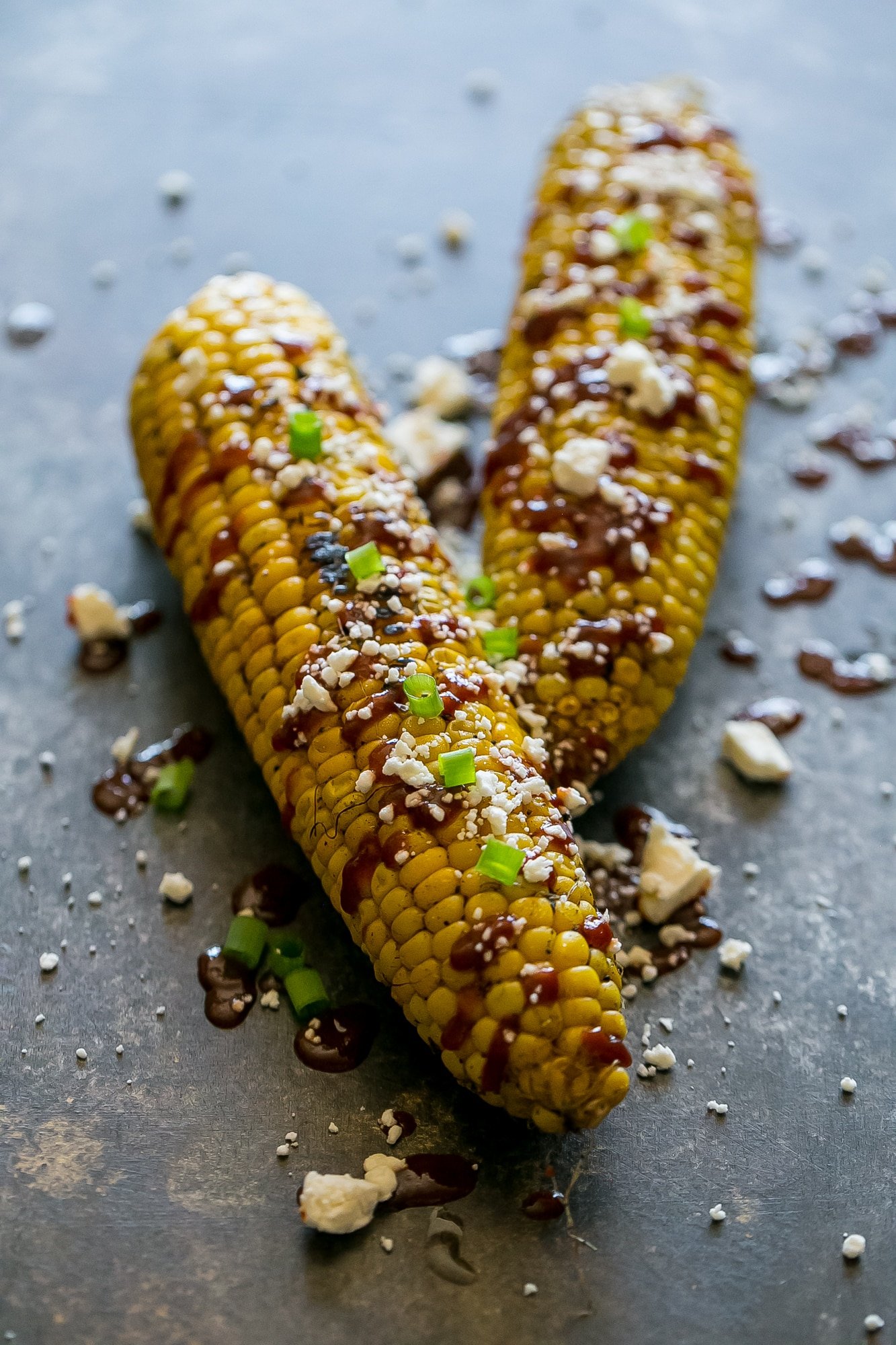 grilled corn smothered with sauce, cheese, and green onions