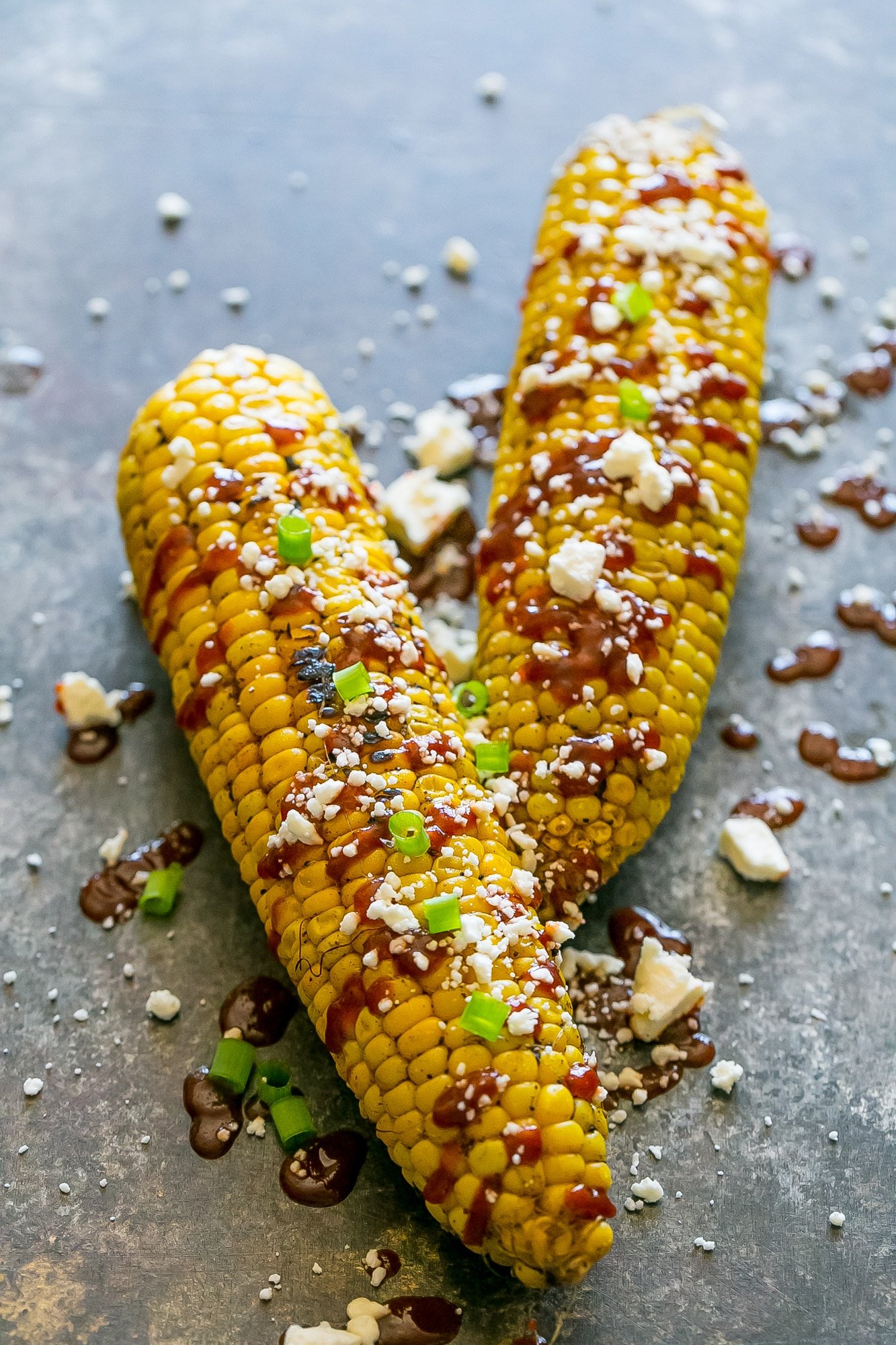 grilled corn smothered with sauce, cheese, and green onions