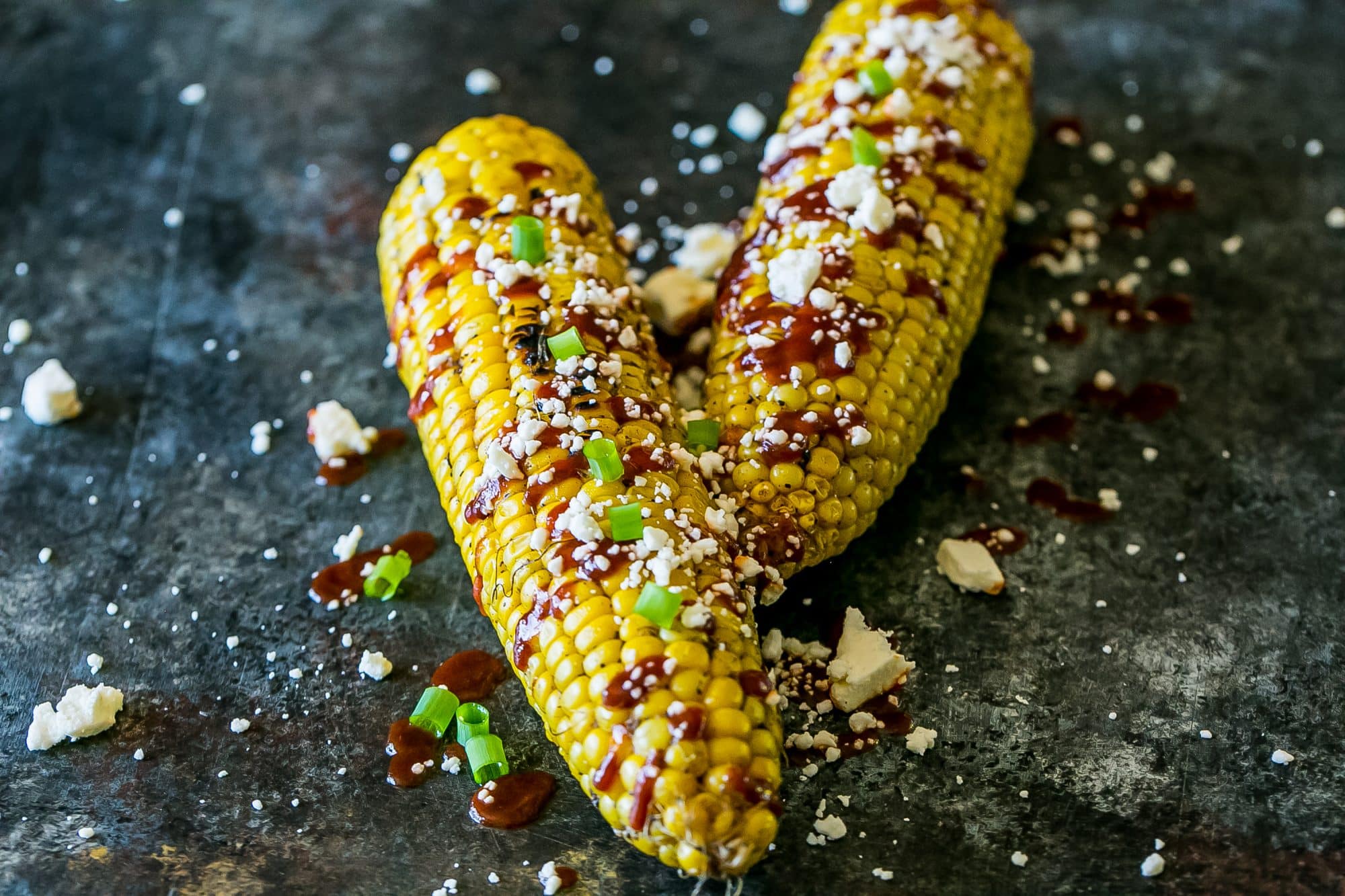 grilled corn smothered with sauce, cheese, and green onions