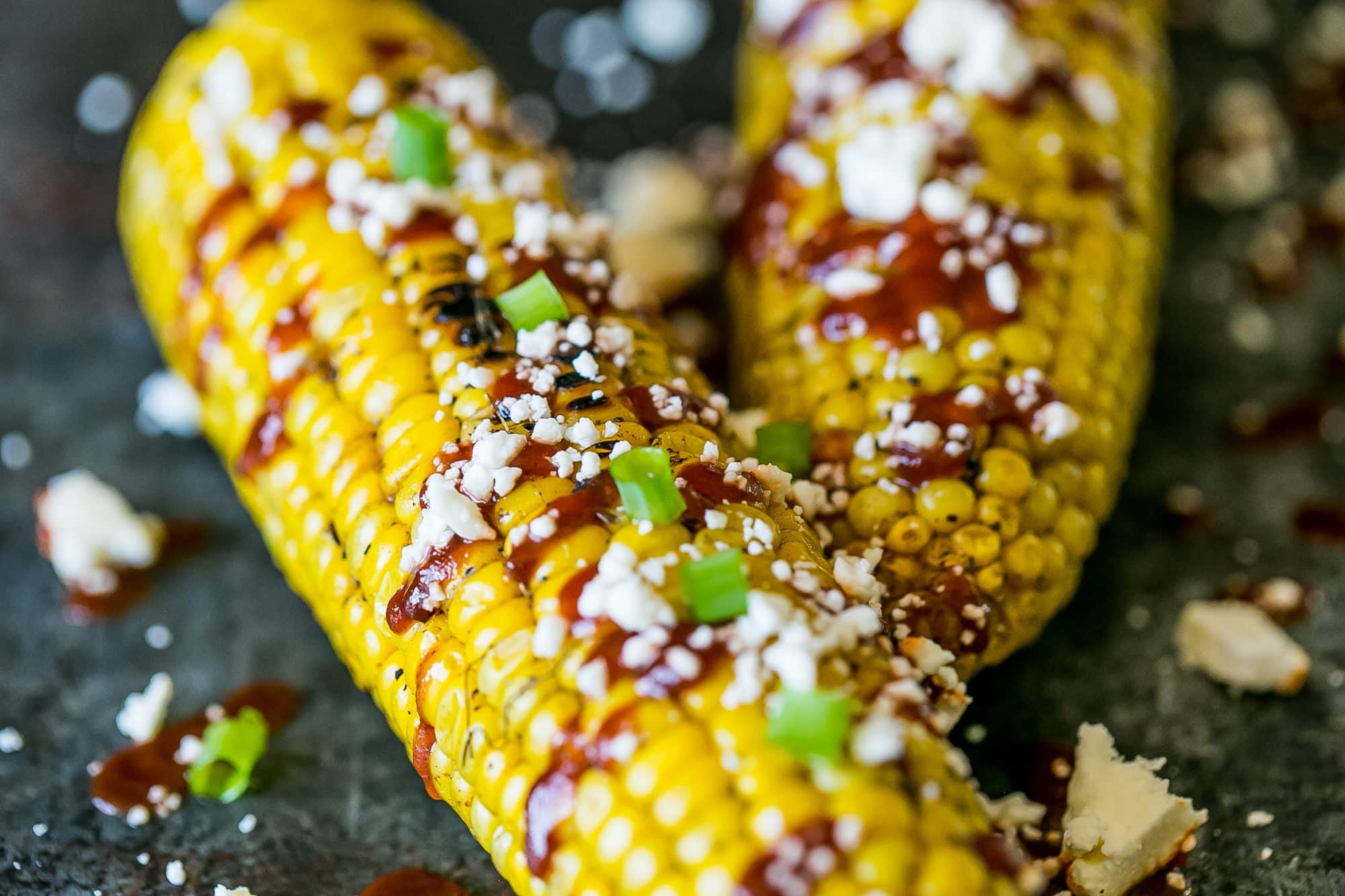 grilled corn smothered with sauce, cheese, and green onions