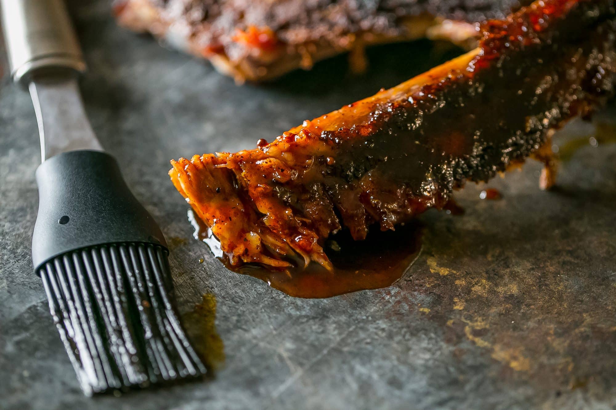 pork rib in sauce with a silicone brush