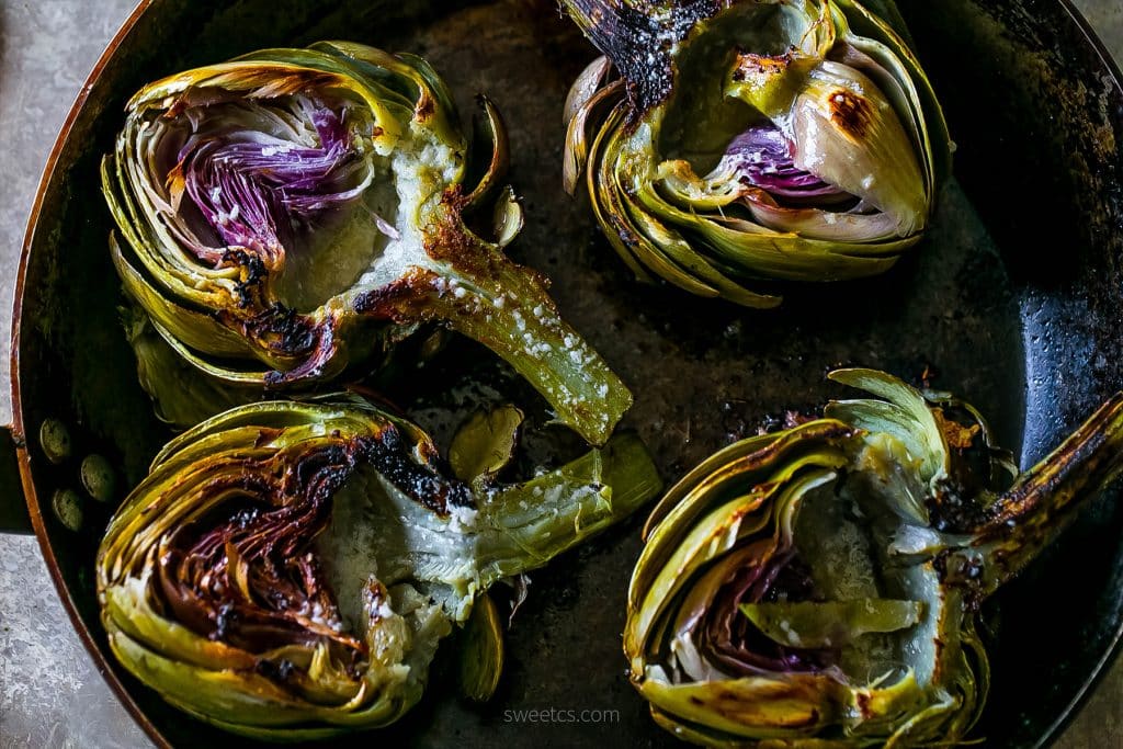 charred artichokes with butter on them