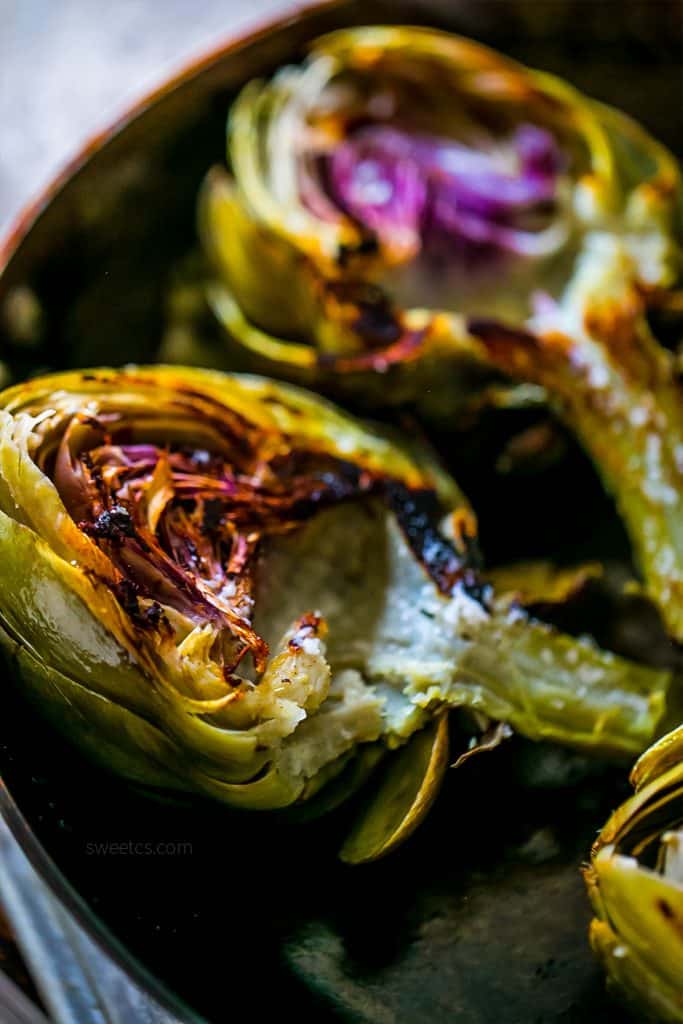 charred artichokes with butter on them