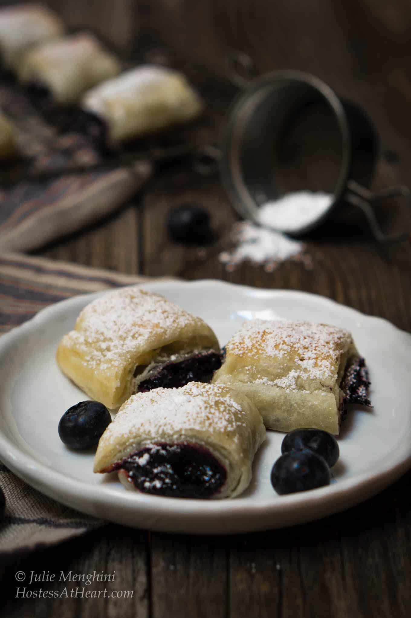 puff pastry wrapped around blueberry jam on a plate with blueberries on it