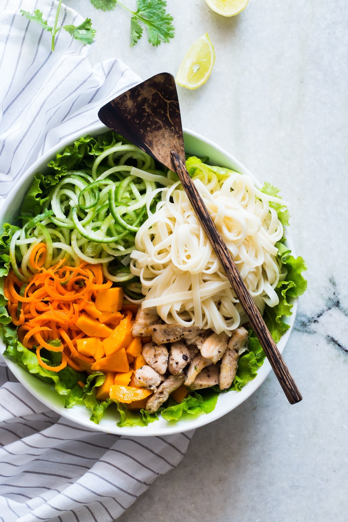 bowl of noodles, cucumber noodles, carrot noodles, mango, chicken, and lettuce