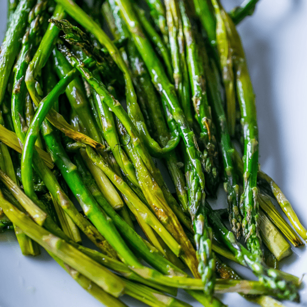 A plate of pan-fried asparagus on a white plate.