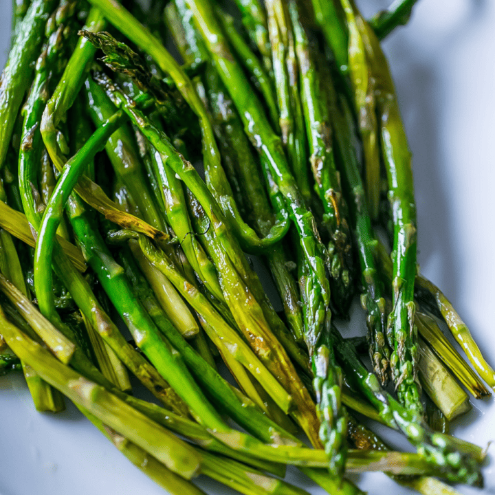 A plate of pan-fried asparagus on a white plate.