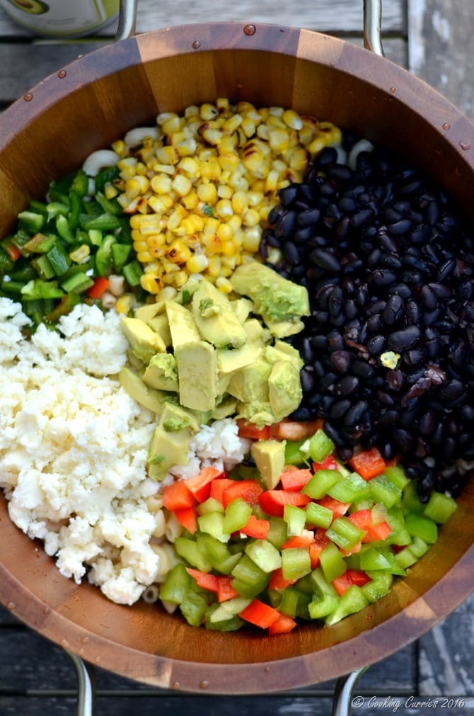 noodles, peppers, creamy dressing, corn, and black beans, avocado, and cheese, all in a bowl. 