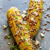 Grilled corn on the cob topped with sriracha cheese.