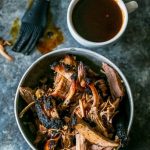 Bbq pulled pork in a bowl next to a cup of coffee, featuring the best smoked pork butt and a smoked pulled pork recipe.