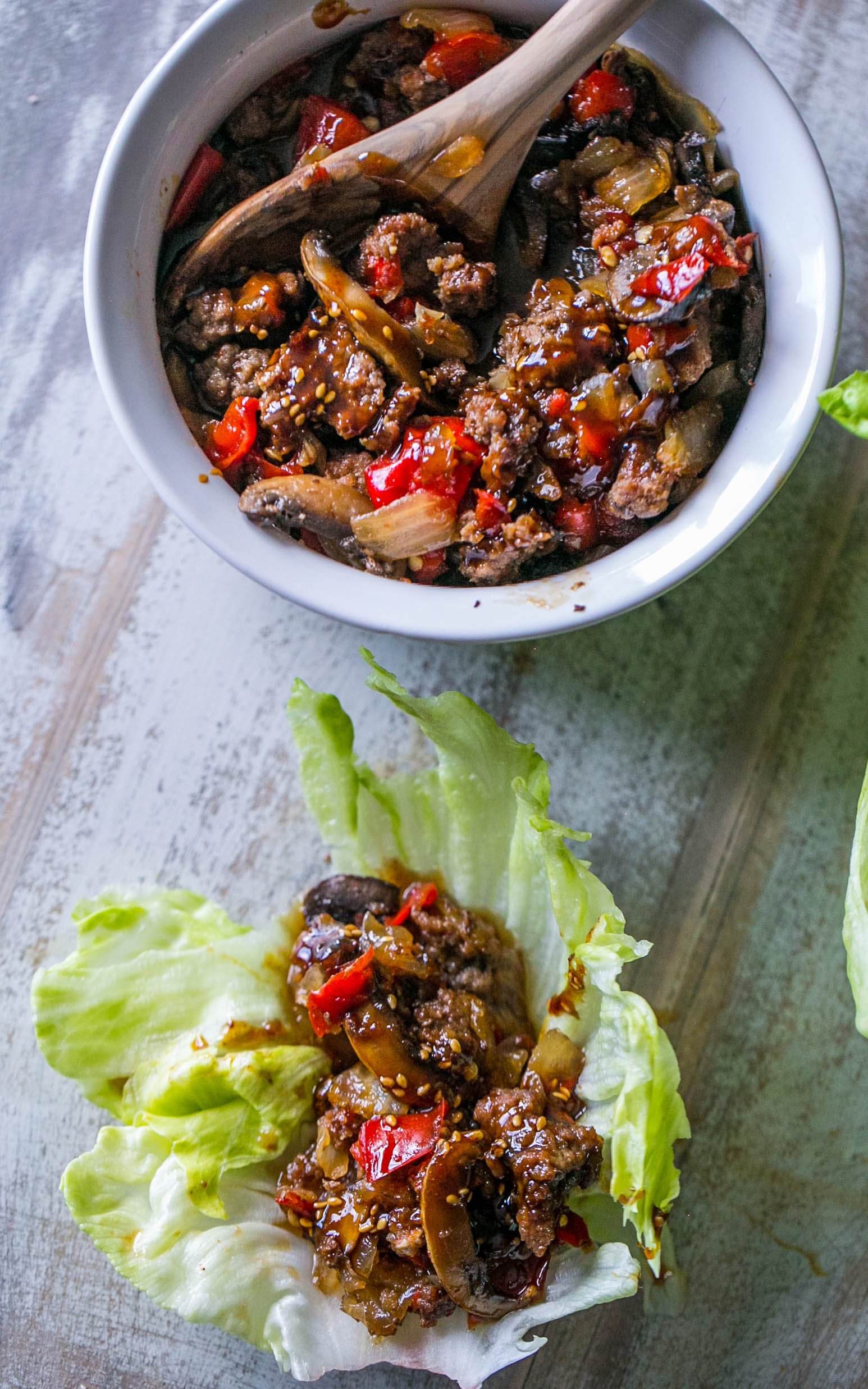 sweet chili beef and mushrooms in a lettuce wrap with sesame seeds on it