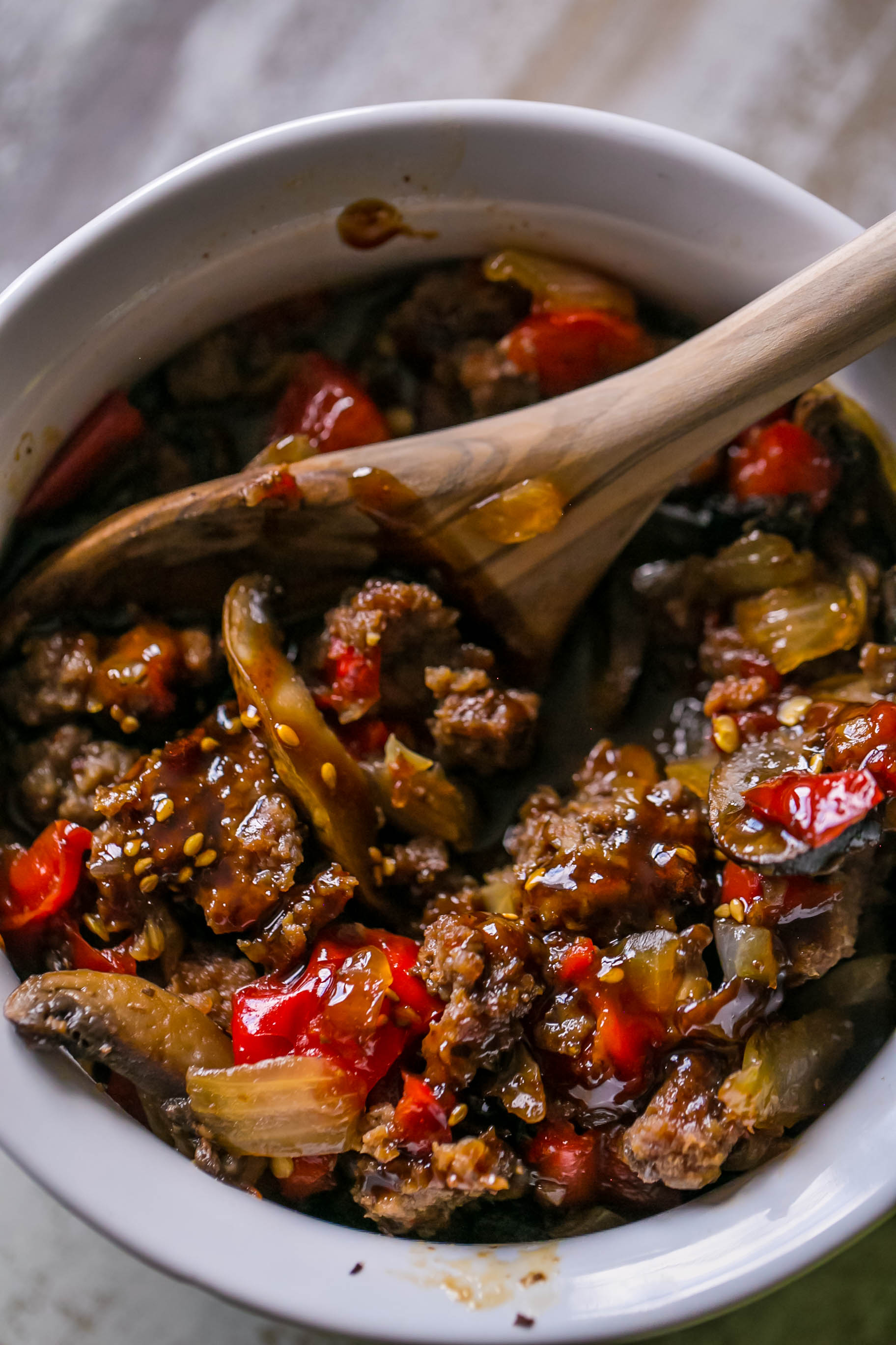 sweet chili beef and mushrooms in a white bowl with a spoon in it. 