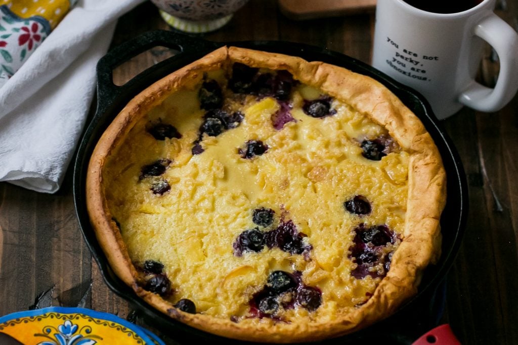 pancake in a cash iron skillet with blueberries and peaches