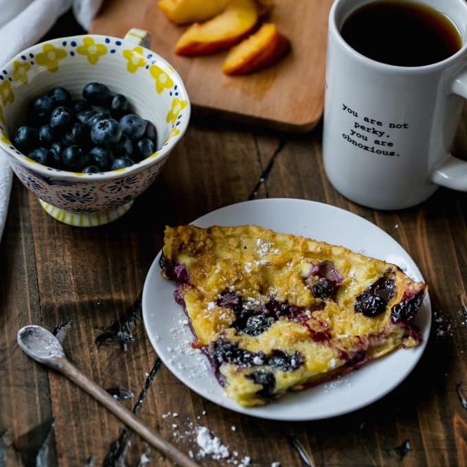 pancake in a cash iron skillet with blueberries and peaches