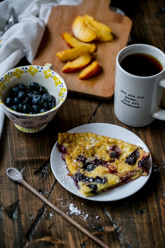 pancake in a cash iron skillet with blueberries and peaches