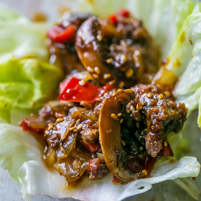 sweet chili beef and mushrooms in a lettuce wrap with sesame seeds on it