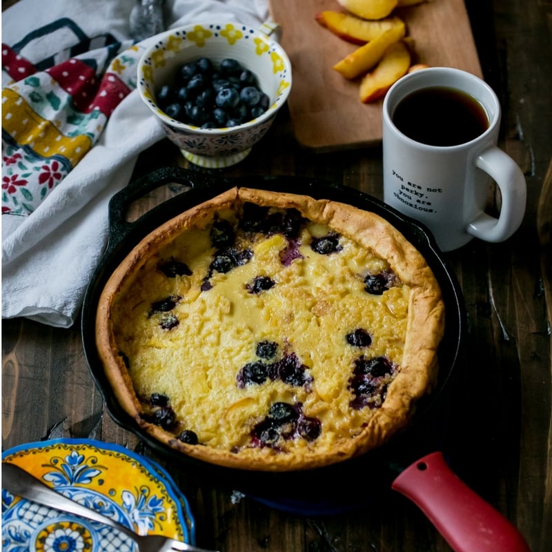 pancake in a cash iron skillet with blueberries and peaches