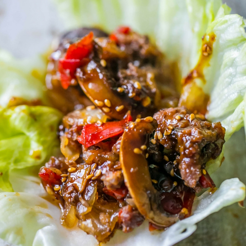 sweet chili beef and mushrooms in a lettuce wrap with sesame seeds on it