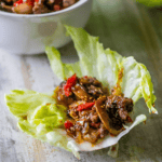 Savory sweet chili beef and vegetables served in a fresh lettuce wrap on a wooden surface.