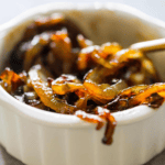 A white ramekin filled with honey whiskey caramelized onions, with a utensil partially visible on the right side.