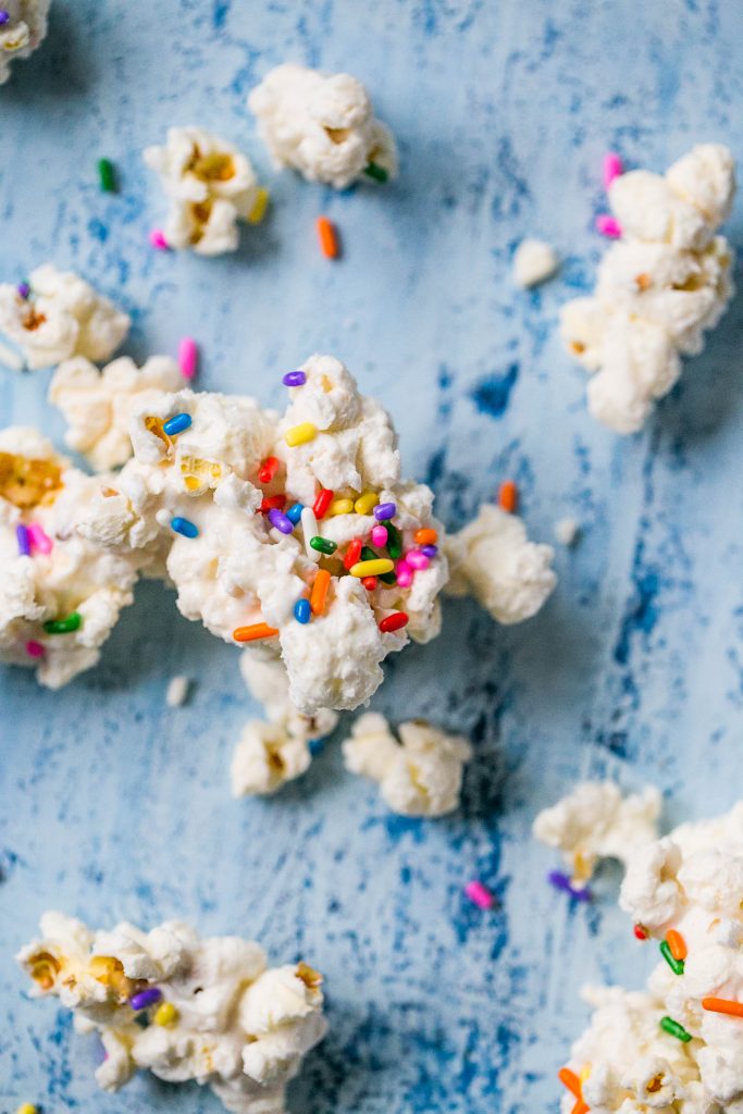 popcorn covered in white chocolate with colorful sprinkles on it