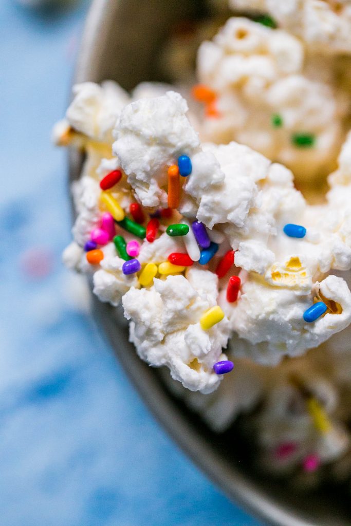 popcorn covered in white chocolate with colorful sprinkles on it