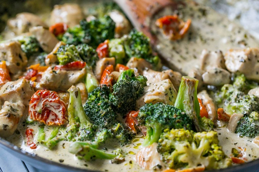 Creamy chicken broccoli alfredo in a bowl with a wooden spoon