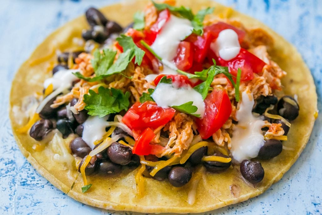 shredded chicken tacos with sour cream, cilantro, black beans, and salsa on them