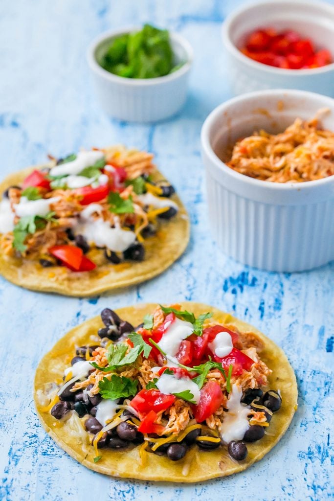 shredded chicken tacos with sour cream, cilantro, black beans, and salsa on them