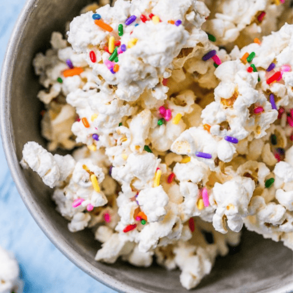 A bowl of cake batter popcorn with sprinkles in it.
