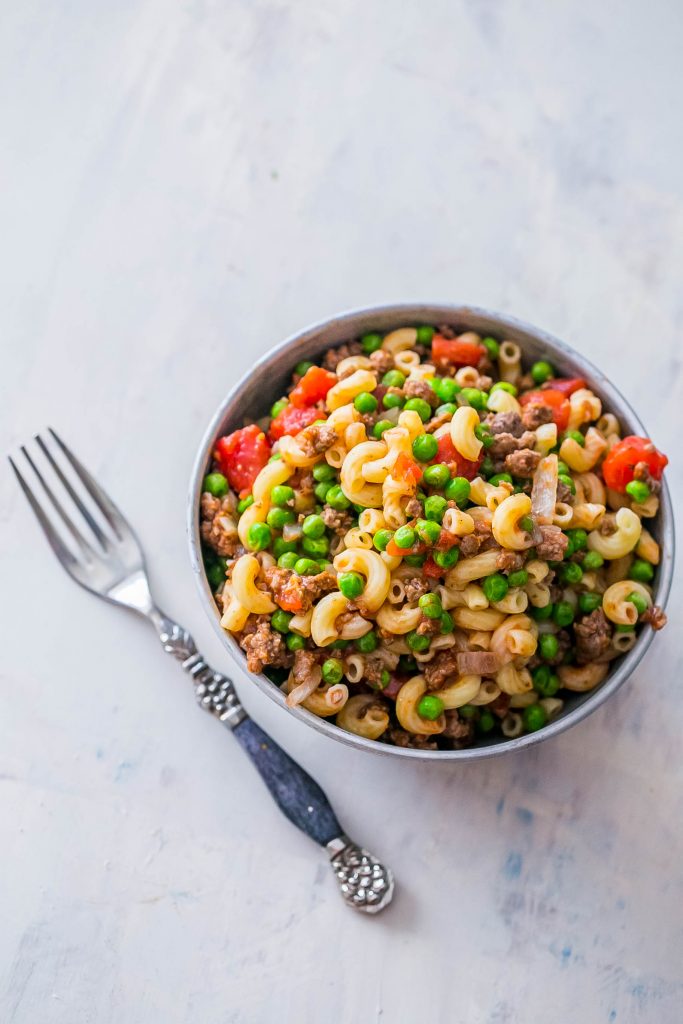 noodles with peas, beef, and tomatoes in it