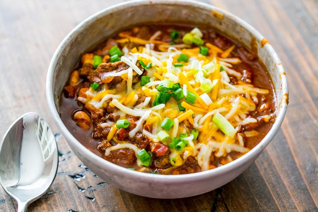 chili in a bowl with cheese and chives on top.