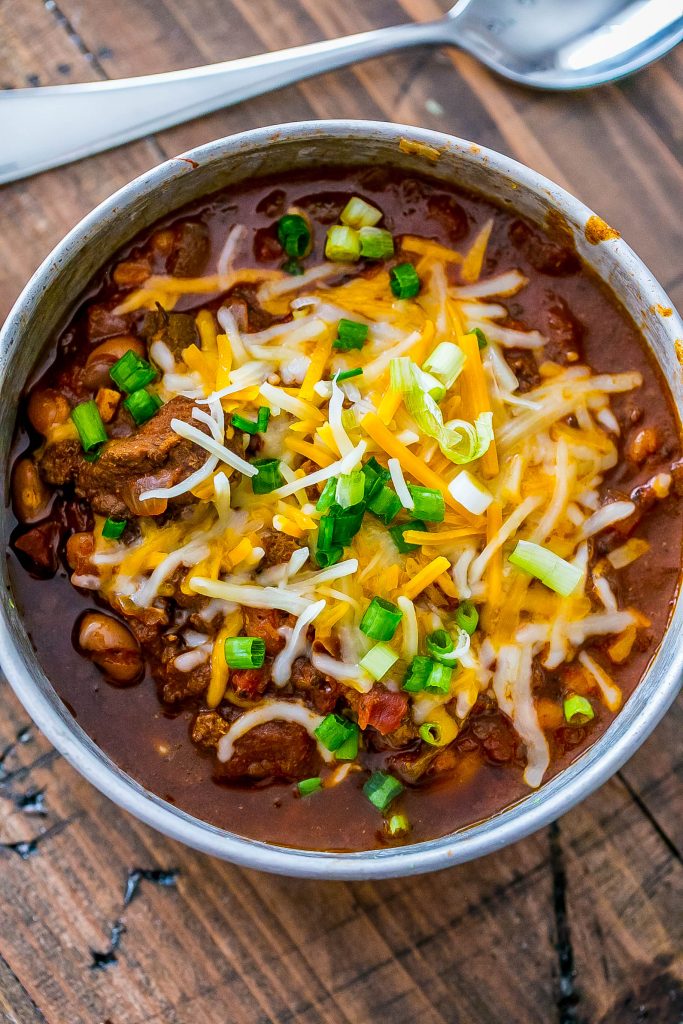 chili in a bowl with cheese and chives on top.
