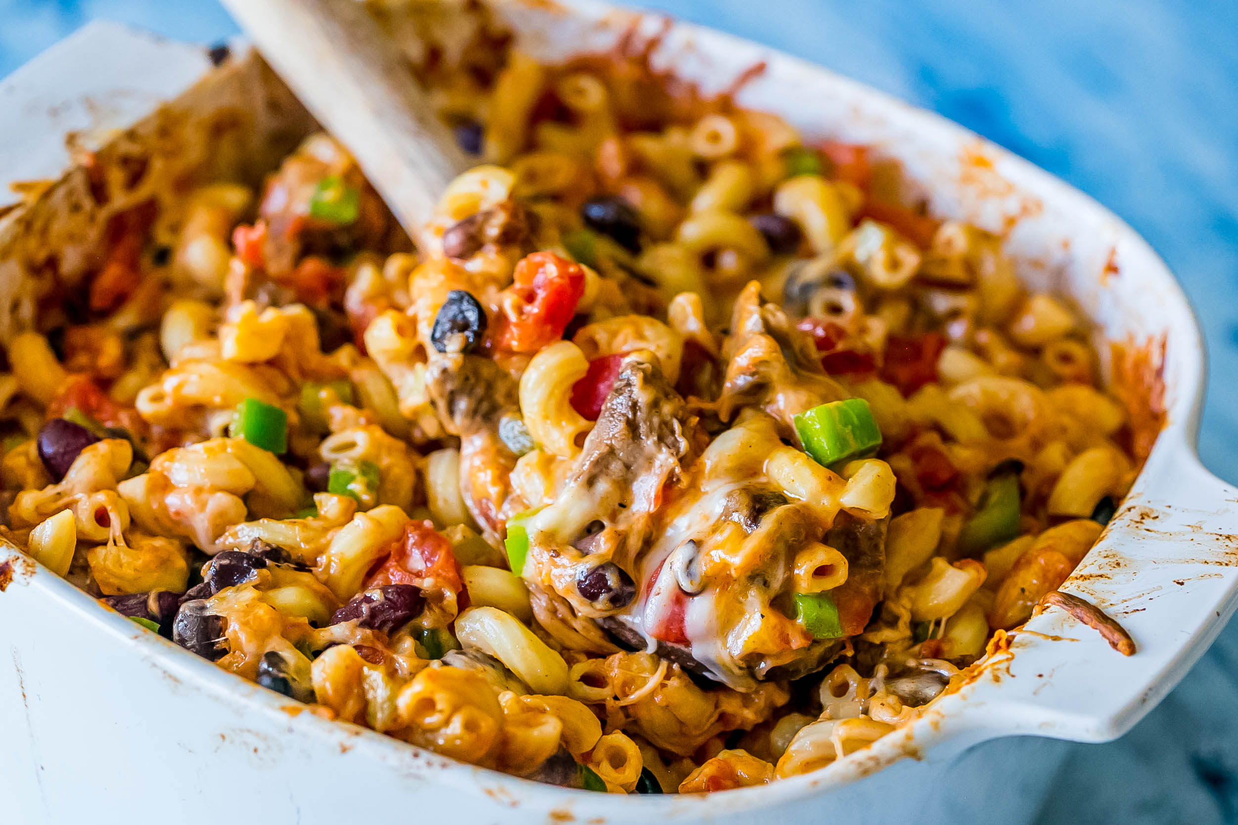 casserole dish with bell peppers, cheese, beans, diced tomatoes, pasta, and steak