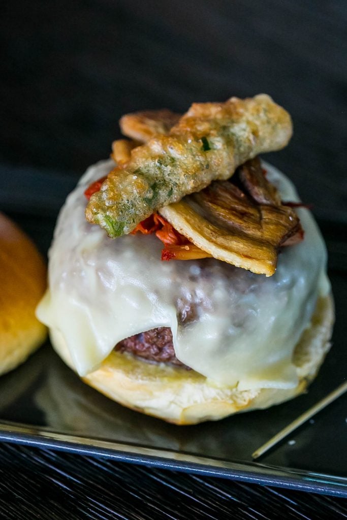 bun with burger and fried vegetables on it